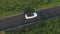 Aerial shot of white convertible car riding through empty rural road. Four young unrecognizable women travelling at