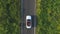 Aerial shot of white convertible car riding through empty rural road. Four young unrecognizable women travelling at