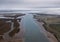 Aerial shot of a wide river slowly flowing through the vast valley