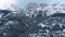 Aerial shot of wooded mountain slopes and peaks in white snow and haze in Kananaskis, Alberta, Canada