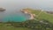 An aerial sideway left to right footage of the Lulworth Cove with sandy beach, crystal blue water, fishing boat, kayakistes and