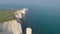 An aerial sideway Left to right footage of the Old Harry Rocks with crystal blue water along beautiful white cliffs under an ama