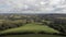 An aerial sideway left to right footage of a rural countryside rolling hills with grassy field, forest and crop field under a ma