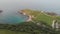 An aerial sideway right to left footage of the Lulworth Cove with sandy beach, crystal blue water, fishing boat, kayakistes and