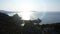 Aerial silhouette of a young loving couple standing on the top of a mountain over the sea at sunrise and kissing. Flight