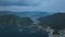 Aerial slide over rugged coastal area and bay with light morning fog