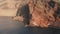 Aerial slider view to old coastal road under a massive layered rock