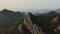 Aerial slow motion footage of a rocky mountain range covered with autumn forest and a sea bay on the horizon. Soothing