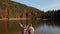 aerial slow motion view of couple hikers man and woman on shore of beautiful famous mountain lake Synevir in Ukraine