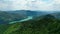 Aerial slow movement around mountains surrounded by growing dense trees and river in Romania