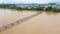 Aerial slowmotion shot of a wooden bridge across the river in Asia with motorbikes riding on it. Dangerous