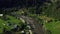 Aerial small mountain village among vivid green trees warm summer sunny day