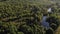 Aerial smooth flyover above of green forest. Lake stretches out between green trees. Non-urban landscape form birds eye view