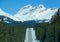 AERIAL: Spectacular view of snowy Canadian Rockies towering above empty road.