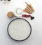 Aerial still life with a round mold filled with cream, cookies, milk bottle, gooseberries, blackberries and round wafers