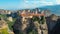 AERIAL: Stunning view of a rural town built on top of stunning towering boulder.