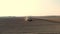 Aerial survey, a large tractor rides through a plowed field of black soil, raising a cloud of dust behind it. planting