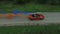 Aerial survey of red cabrioled goes on the road and couple using colored smoke.Flying over classic red convertible car