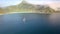 Aerial take off view of a yacht floating in the sea and the cloudy mountains