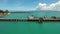 Aerial: Three Young Mixed Race Friends Sitting on Pier. Koh Phangan, Thailand. Drone Fly Away Selfie. HD Slowmotion.