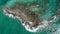 Aerial top down shot of a stone shoreline and turquoise sea water illuminated by the sun