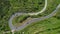 AERIAL TOP DOWN: Tourists on road trip are driving through a sharp hairpin turn.