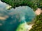 Aerial top down view of beautiful green waters of lake Gela. Birds eye view of scenic emerald lake surrounded by pine forests