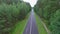 Aerial top down view of car driving on country road in forest in the evening at twilight. Cinematic drone shot flying over asphalt