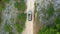 Aerial Top Down View Of Car Driving Offroad on Gravel Trail Path In Beautiful Nature with Rocks and Pine Trees.