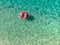 Aerial top down view of cute young girl floating on toy ring at Myrtos beach, the most beautiful beach of Kefalonia, a large coast