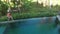 Aerial Top Down View of Infinity pool at luxurious exotic island. Woman walking on edge of pool and enjoy jungle view