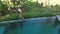 Aerial Top Down View of Infinity pool at luxurious exotic island. Woman walking on edge of pool and enjoy jungle view