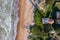 Aerial top down view of lighthouse with red top and white base. Blue sea and sand beach. Pape lighthouse