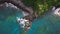 Aerial top down view of rocky coastline with green cliffside and blue sea.