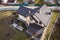 Aerial top view of building steep shingle roof, brick chimneys and small attic window on house top with metal tile roof. Roofing,