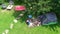 Aerial top view of campsite from above, mother and daughter having fun, tent and camping equipment under tree, family vacation