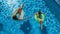 Aerial top view of children in swimming pool from above, happy kids swim on inflatable ring donuts and have fun in water