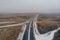 Aerial or top view from drone to winter asphalt highway or motorway road in countryside with car and truck traffic driving fast