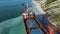 Aerial top view of an empty, red barge moored near the beautiful blue sea shore. Big Industrial ship standing near the