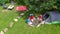 Aerial top view of family in campsite from above, parents and kids relax and have fun in park, tent and camping equipment
