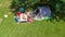 Aerial top view of family in campsite from above, parents and kids relax and have fun in park, tent and camping equipment