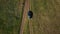 Aerial top view of grey car driving on wet rural road in green field.