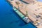 Aerial top view huge cargo ship moored at the pier at the port, loading goods, ore mineral bulk cargo in railway cars, concrete