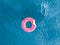 Aerial top view inflatable pink donut in transparent blue sea