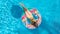 Aerial top view of little girl in swimming pool from above, kid swims on inflatable ring donut , child has fun in water