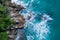 Aerial top view of ocean`s beautiful waves crashing on the rocky island coast
