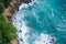 Aerial top view of ocean`s beautiful waves and rocky coast with greenery