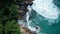 Aerial top view of ocean`s beautiful waves and rocky coast with greenery