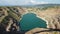 Aerial top view on opencast mining quarry with flooded bottom, turquoise surface of the lake. Quarry pond overgrown with