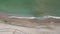 Aerial top view of sea waves hitting the beach with sea water.